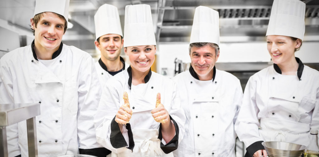 Culinary class with pastry teacher giving thumbs up in kitchen