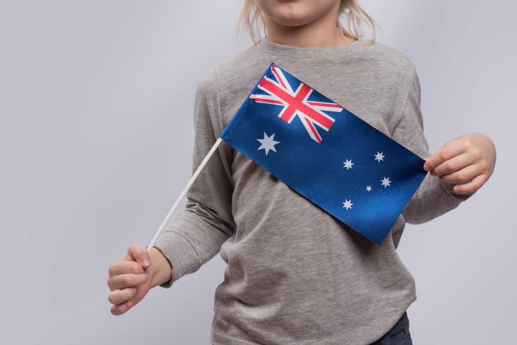 Child holds flag of Australia. Close up. Traveling with children in Australia.